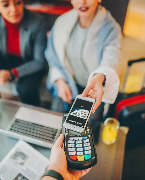 Lady using her smart phone to pay at a credit card terminal